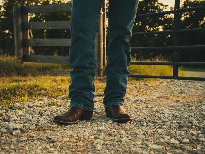 Close-up of boots and jeans on a gravel ranch road