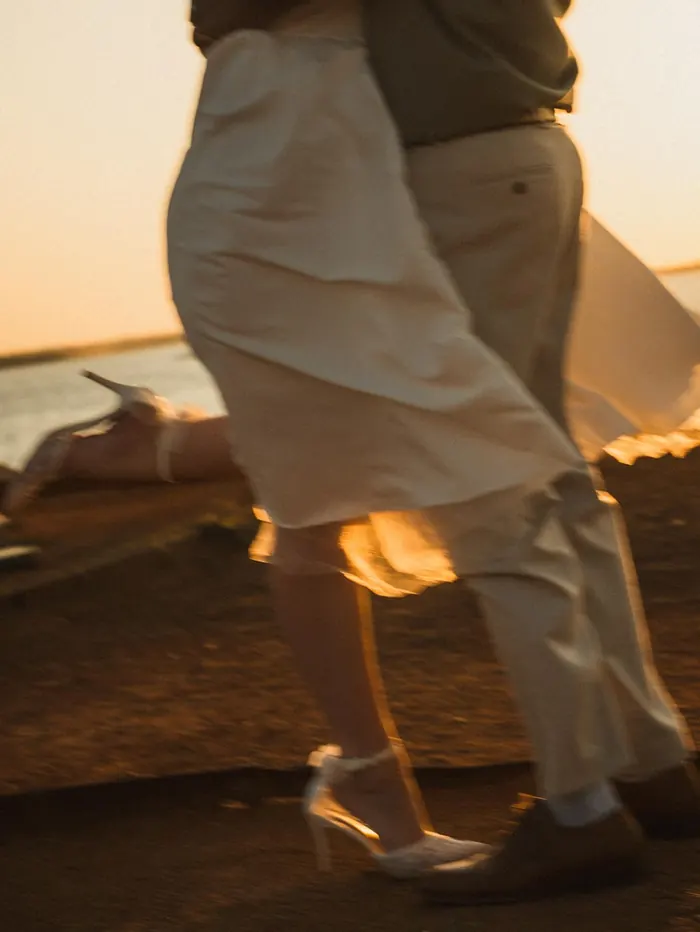 Couple dancing on the shoreline at sunset