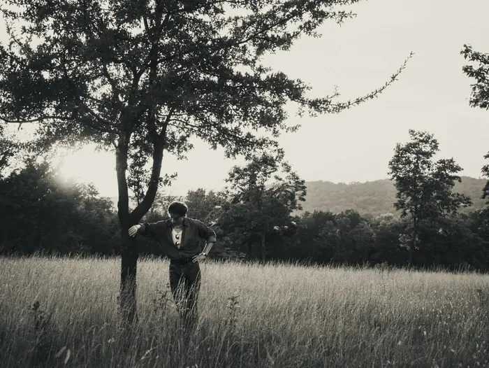Black and white photo of a couple under a tree in an open field