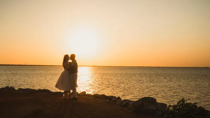 Couple silhouetted against a lake sunset