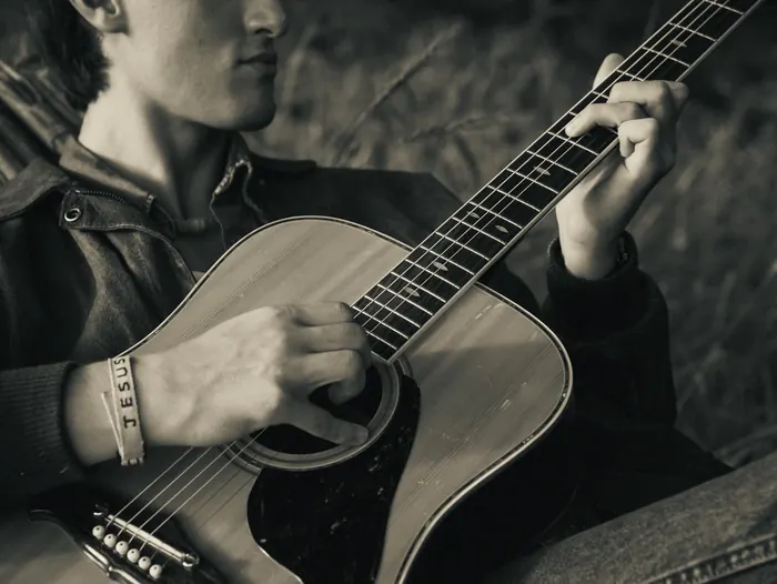 Black and white close-up of hands playing an acoustic guitar