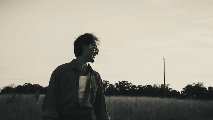 Black and white portrait of a young man looking across a field