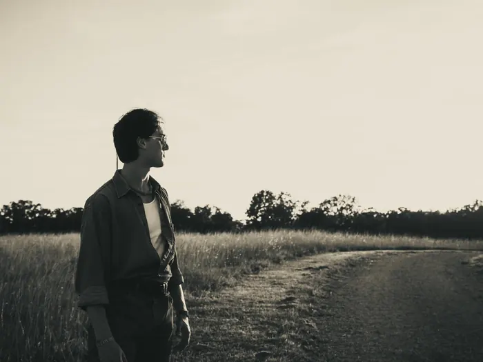 Black and white portrait of a young man beside a country road