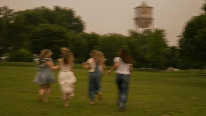 Group of friends running across a park lawn