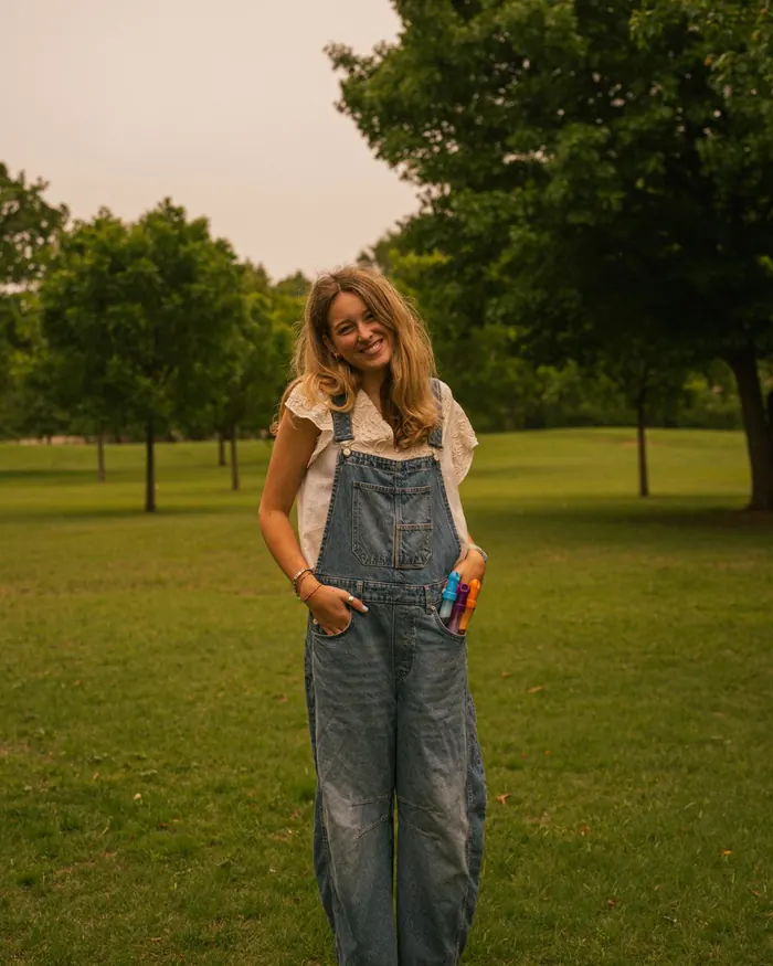 Senior portrait of a smiling girl in overalls in a park