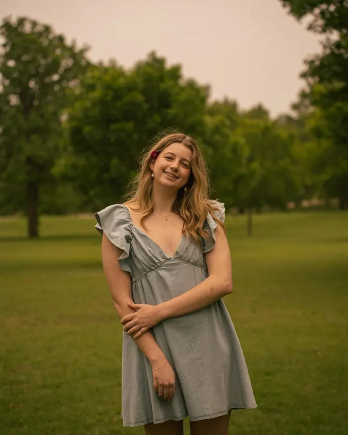 Senior portrait of a smiling girl in a gray dress on a lawn