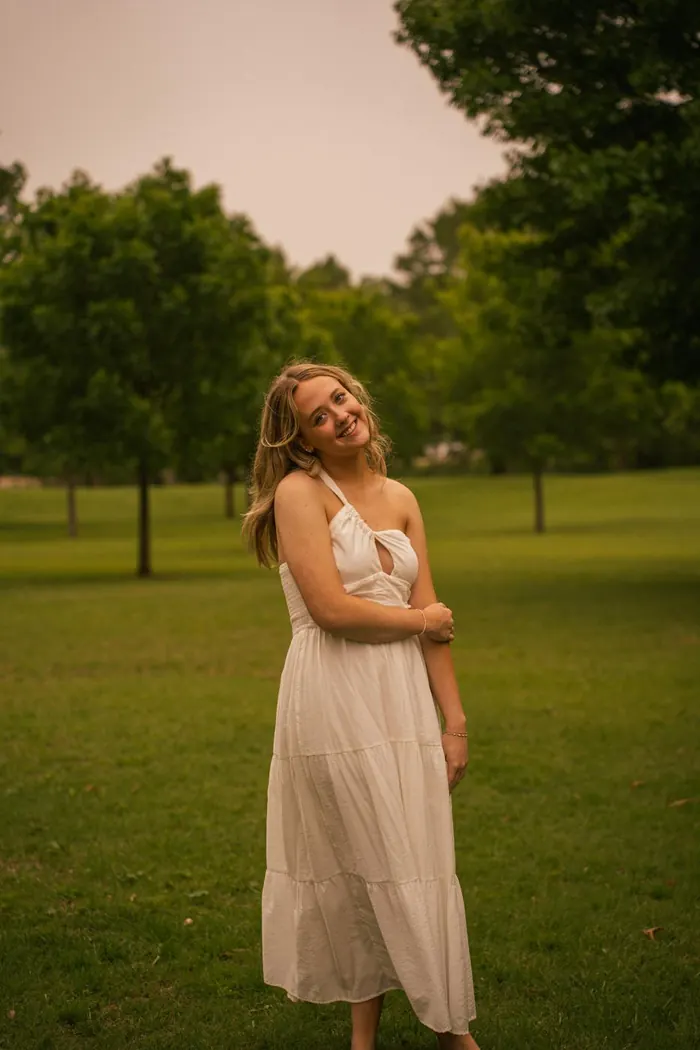 Senior portrait of a girl in a white sundress under the trees