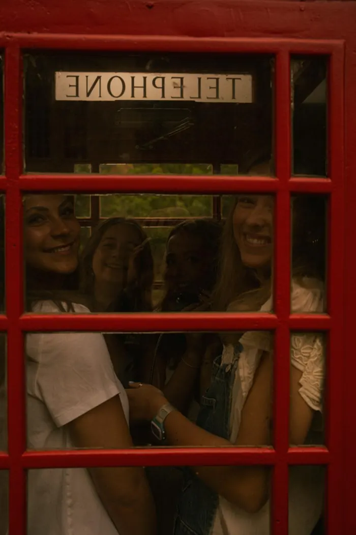 Friends squeezed into a red telephone booth