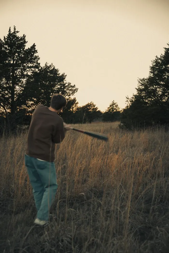 Young man walking through a tall grass field