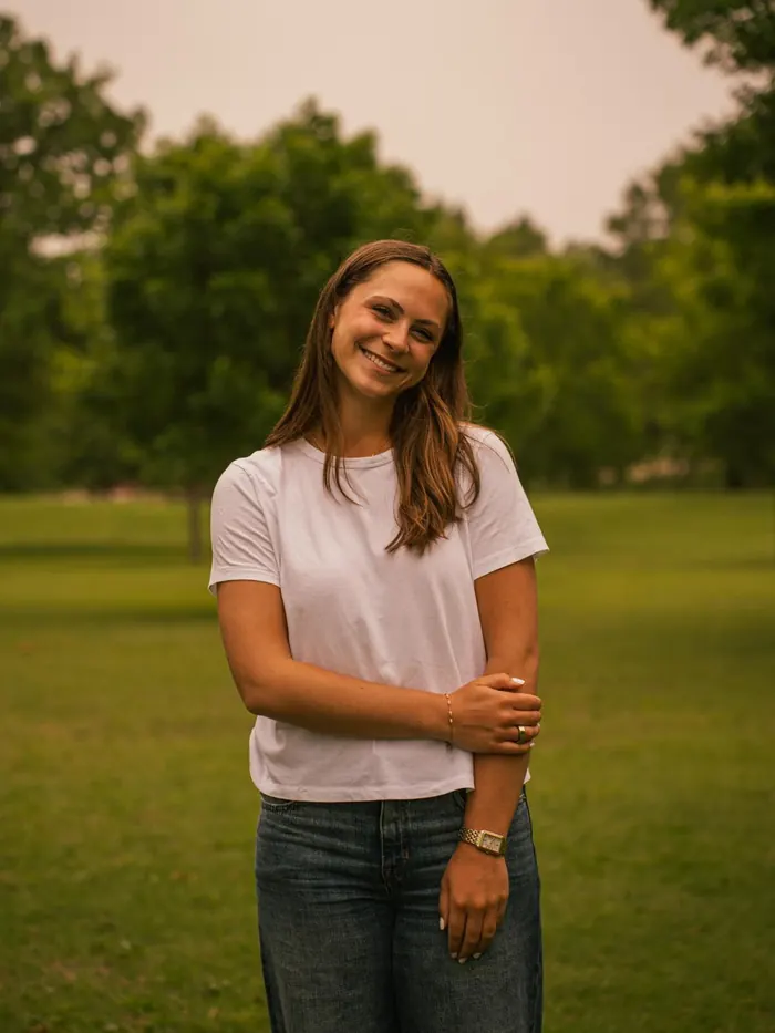 Senior portrait of a smiling girl in a white t-shirt on campus