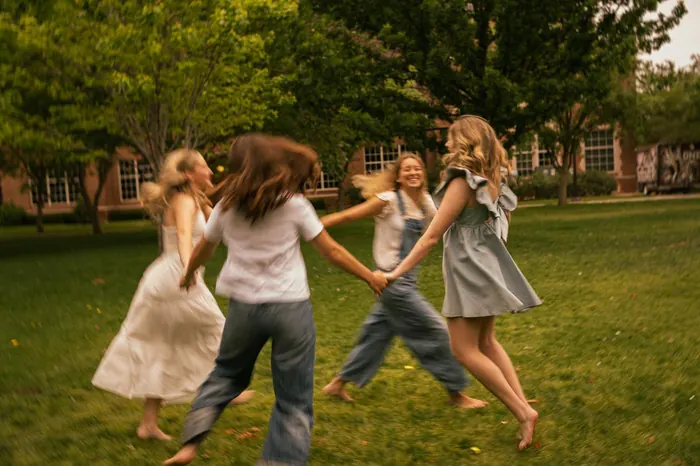Friends spinning in a circle holding hands on a lawn